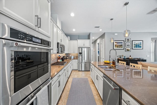 13819 American Prairie Pl, Bradenton, FL 34211 - kitchen with stainless steel appliances, a sink, backsplash, white cabinets, and pendant lighting