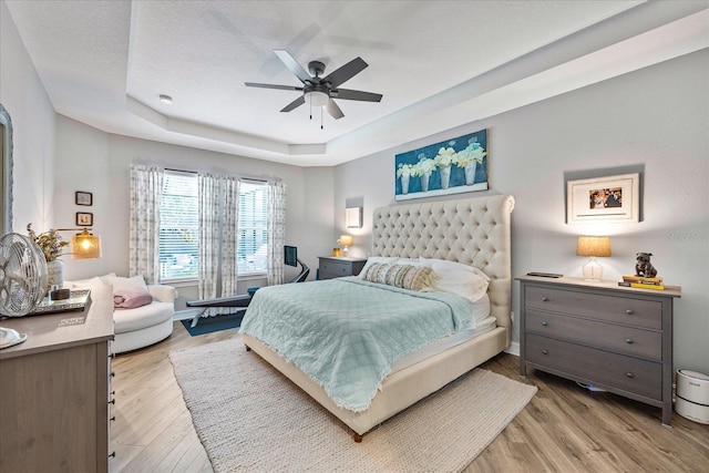 13819 American Prairie Pl, Bradenton, FL 34211 - bedroom with a raised ceiling, light wood-type flooring, and a ceiling fan