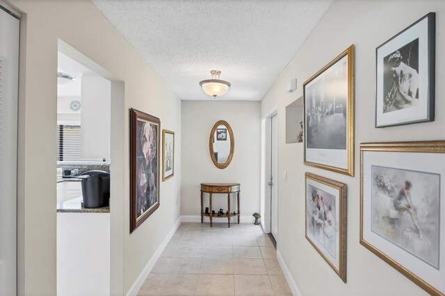 3914 Glen Oaks Manor Dr, Sarasota, FL 34232 - hall featuring a textured ceiling, light tile patterned flooring, and baseboards