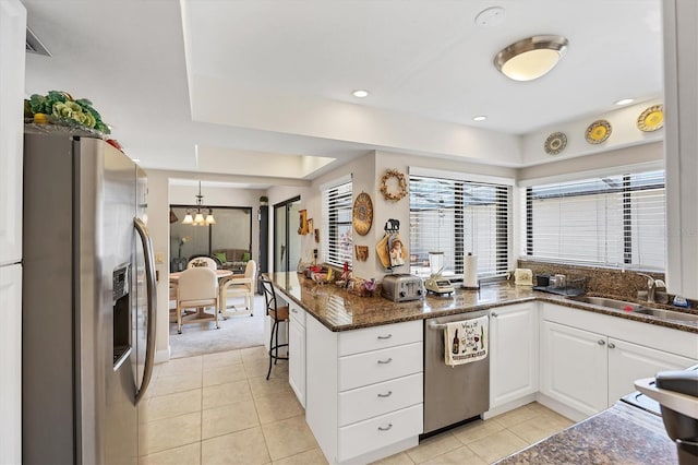 3914 Glen Oaks Manor Dr, Sarasota, FL 34232 - kitchen featuring appliances with stainless steel finishes, a sink, white cabinetry, a chandelier, and light tile patterned floors