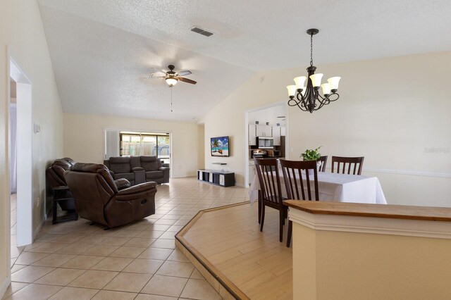 613 E 49th St E, Bradenton, FL 34208 - living room featuring vaulted ceiling, a chandelier, ceiling fan, and light tile patterned floors
