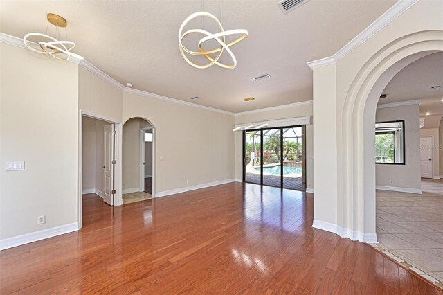 12644 20th St E, Parrish, FL 34219 - empty room with a chandelier, plenty of natural light, wood-type flooring, arched walkways, and ornamental molding