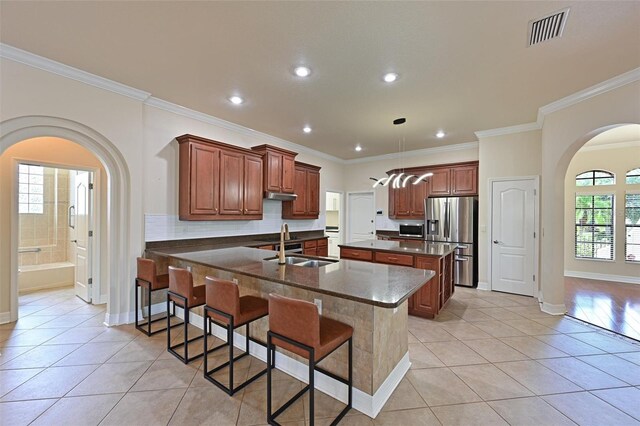 12644 20th St E, Parrish, FL 34219 - kitchen featuring appliances with stainless steel finishes, arched walkways, dark countertops, light tile patterned floors, and a sink