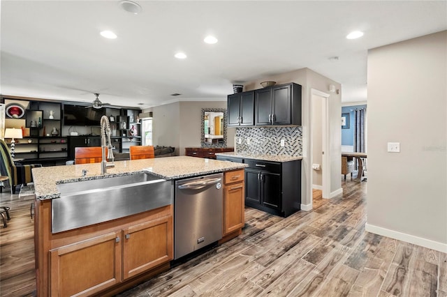 2306 63rd St W Unit 40, Bradenton, FL 34209 - kitchen with stainless steel dishwasher, a sink, light stone countertops, a ceiling fan, and light wood-style floors