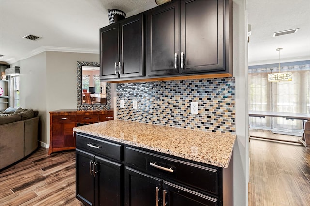 2306 63rd St W Unit 40, Bradenton, FL 34209 - kitchen featuring dark cabinetry, ornamental molding, wood finished floors, decorative backsplash, and open floor plan