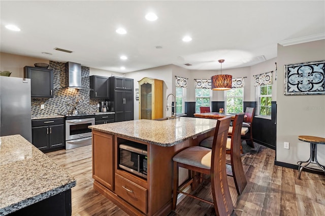 2306 63rd St W Unit 40, Bradenton, FL 34209 - kitchen featuring stainless steel appliances, wall chimney exhaust hood, a sink, tasteful backsplash, and a kitchen bar