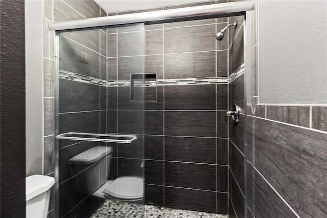 2306 63rd St W Unit 40, Bradenton, FL 34209 - bathroom with toilet, a shower stall, a textured wall, and a wainscoted wall