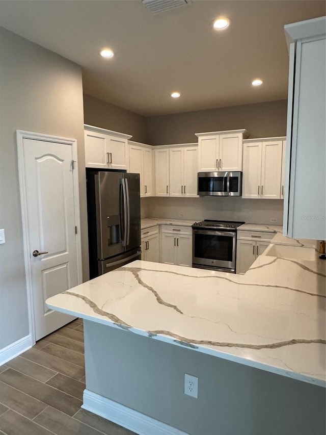 24831 Buckingham Way, Port Charlotte, FL 33980 - kitchen featuring stainless steel appliances, a peninsula, recessed lighting, light stone countertops, and dark wood-style flooring
