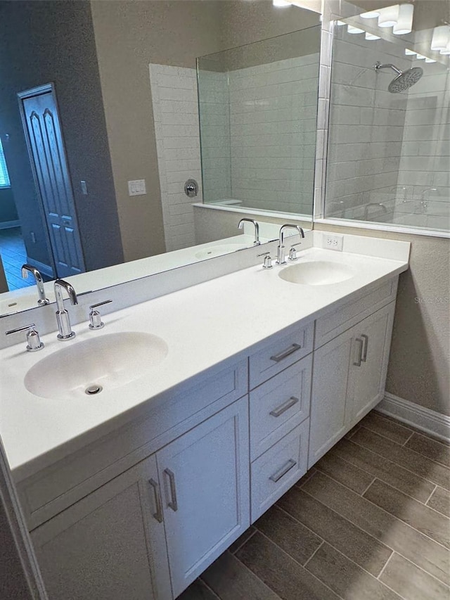 24831 Buckingham Way, Port Charlotte, FL 33980 - bathroom featuring a tile shower, double vanity, wood finish floors, and baseboards