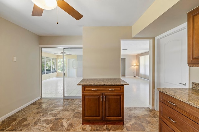 135 Gulfview Rd, Punta Gorda, FL 33950 - kitchen with ceiling fan, baseboards, brown cabinetry, and light stone countertops