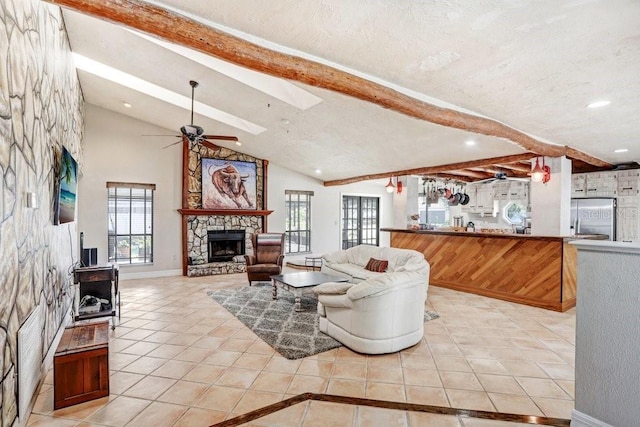 7321 Caladesia Dr, Sarasota, FL 34243 - living room featuring a fireplace, light tile patterned floors, a ceiling fan, a skylight, and baseboards