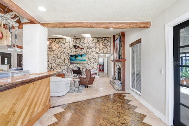 7321 Caladesia Dr, Sarasota, FL 34243 - living area featuring a stone fireplace, beam ceiling, and wood finished floors