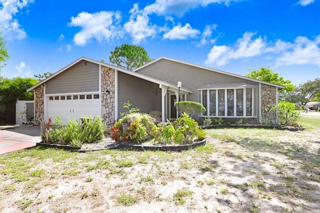 7321 Caladesia Dr, Sarasota, FL 34243 - mid-century inspired home with stone siding, an attached garage, concrete driveway, and a sunroom