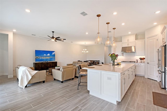 11427 Viani Ter, Palmetto, FL 34221 - kitchen featuring under cabinet range hood, white cabinetry, open floor plan, light countertops, and wood tiled floors
