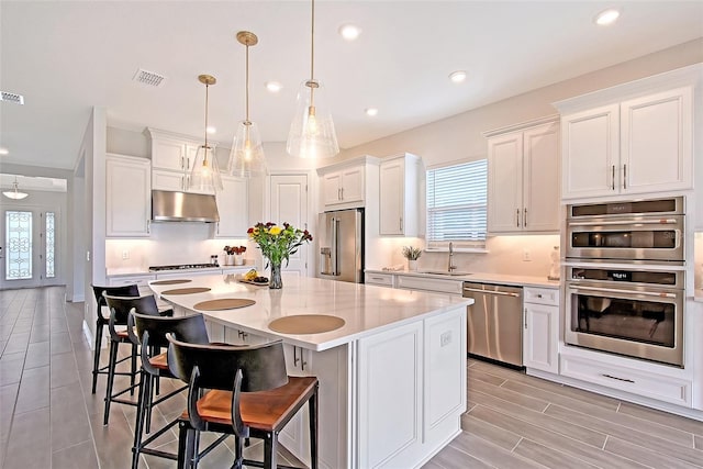 11427 Viani Ter, Palmetto, FL 34221 - kitchen with appliances with stainless steel finishes, under cabinet range hood, light countertops, white cabinets, and a kitchen bar