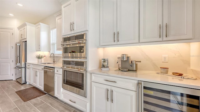 11427 Viani Ter, Palmetto, FL 34221 - kitchen with appliances with stainless steel finishes, beverage cooler, a sink, white cabinets, and light countertops