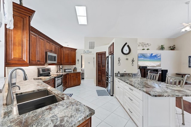4585 Dover Street Cir E, Bradenton, FL 34203 - kitchen featuring stainless steel appliances, a sink, a kitchen breakfast bar, a peninsula, and light stone counters