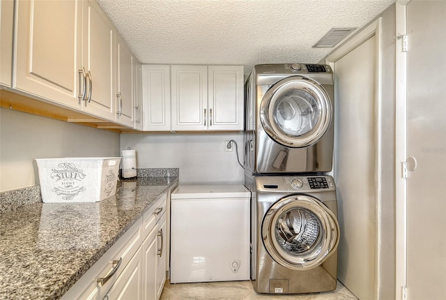 8779 Midnight Pass Rd Unit 506H, Sarasota, FL 34242 - washroom featuring stacked washer / drying machine, cabinet space, a textured ceiling, and light tile patterned floors