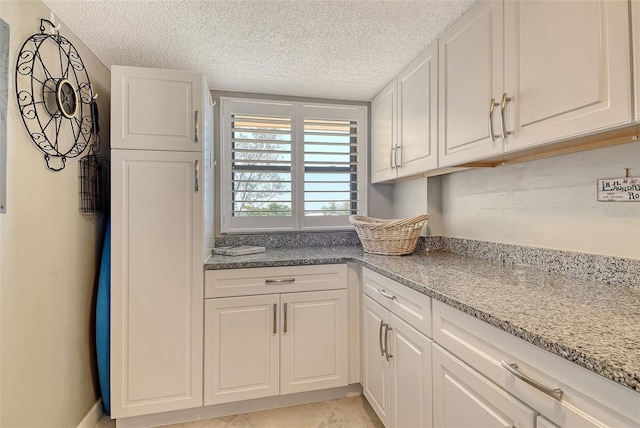 8779 Midnight Pass Rd Unit 506H, Sarasota, FL 34242 - kitchen featuring a textured ceiling, white cabinets, and light stone counters