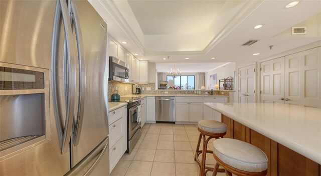1465 Gulf Of Mexico Dr Unit 502, Longboat Key, FL 34228 - kitchen featuring appliances with stainless steel finishes, a peninsula, white cabinetry, light countertops, and backsplash