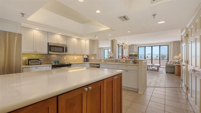 1465 Gulf Of Mexico Dr Unit 502, Longboat Key, FL 34228 - kitchen with stainless steel appliances, open floor plan, light countertops, tasteful backsplash, and a peninsula