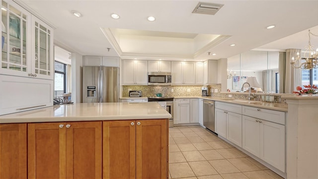 1465 Gulf Of Mexico Dr Unit 502, Longboat Key, FL 34228 - kitchen with appliances with stainless steel finishes, a sink, a raised ceiling, a peninsula, and a chandelier