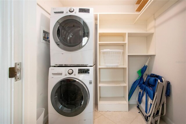 3745 Almeria Ave Unit 7S, Sarasota, FL 34239 - laundry area featuring stacked washer and clothes dryer, tile patterned flooring, and baseboards