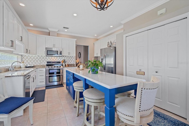 12322 Tall Pines Way, Lakewood Ranch, FL 34202 - kitchen with appliances with stainless steel finishes, a kitchen island, white cabinetry, decorative backsplash, and a sink