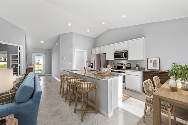 10547 Kidron Ave, Englewood, FL 34224 - kitchen featuring appliances with stainless steel finishes, open floor plan, lofted ceiling, a kitchen bar, and light stone countertops