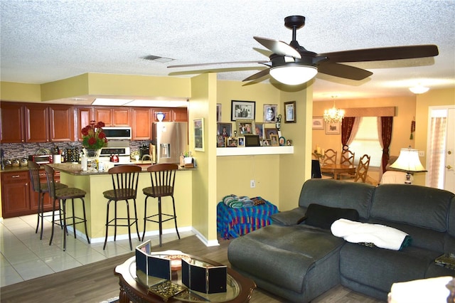6704 Rosemary Dr, Tampa, FL 33625 - living room featuring a ceiling fan, a textured ceiling, a chandelier, and light wood finished floors