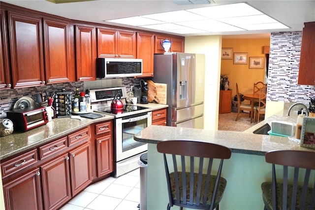 6704 Rosemary Dr, Tampa, FL 33625 - kitchen with stainless steel appliances, tasteful backsplash, a breakfast bar area, stone countertops, and a peninsula