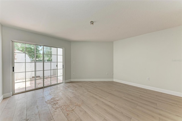 7023 Woodside Oaks Cir Unit 1, Sarasota, FL 34231 - unfurnished room with light wood-type flooring, baseboards, and a textured ceiling