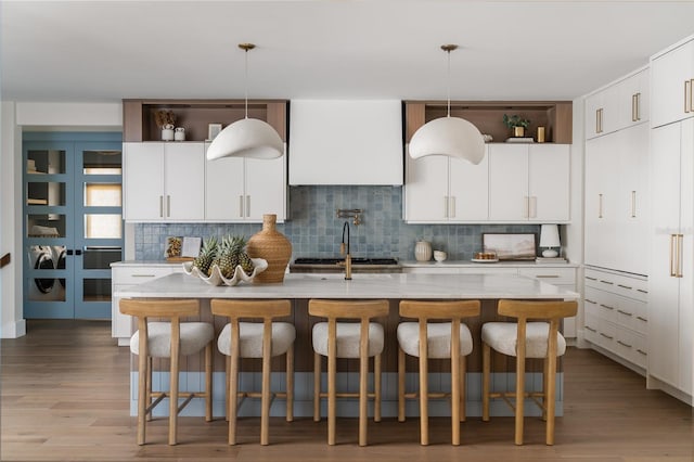 401 39th St, Holmes Beach, FL 34217 - kitchen featuring decorative backsplash, decorative light fixtures, light wood-type flooring, and a center island with sink