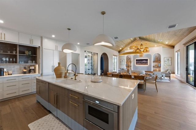 401 39th St, Holmes Beach, FL 34217 - kitchen featuring a sink, open floor plan, stainless steel microwave, white cabinetry, and light wood-type flooring