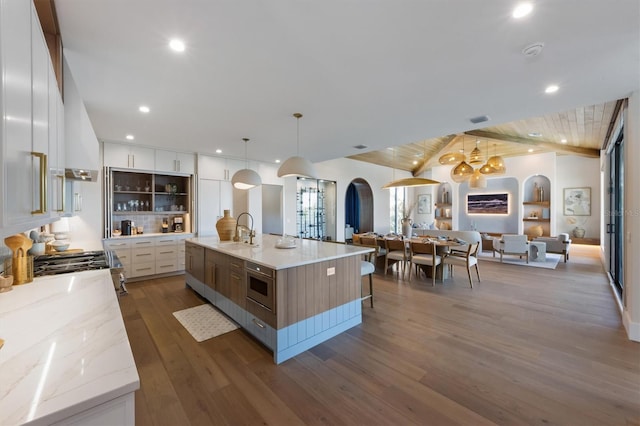 401 39th St, Holmes Beach, FL 34217 - kitchen with arched walkways, a sink, white cabinets, wood finished floors, and recessed lighting