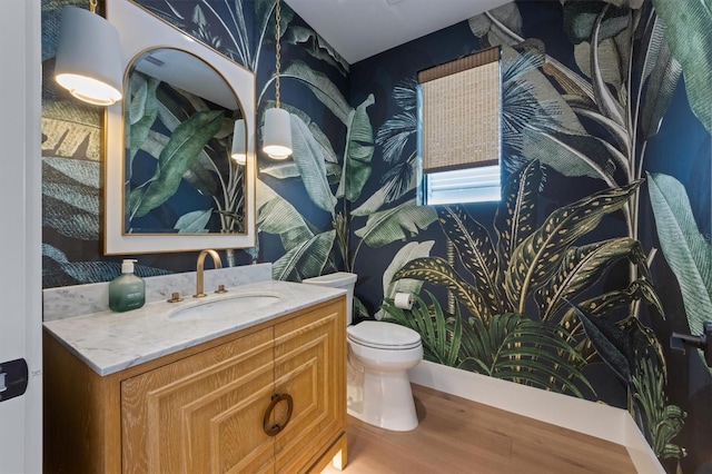 401 39th St, Holmes Beach, FL 34217 - bathroom with wood finished floors, toilet, vanity, and wallpapered walls