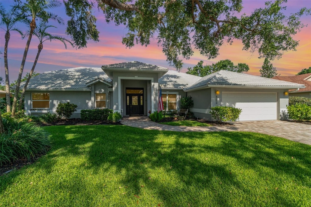 4374 Indian Point Trl, Sarasota, FL 34238 - view of front facade with a garage, a yard, stucco siding, decorative driveway, and a tiled roof