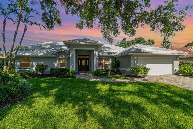 4374 Indian Point Trl, Sarasota, FL 34238 - view of front facade with a garage, a yard, stucco siding, decorative driveway, and a tiled roof