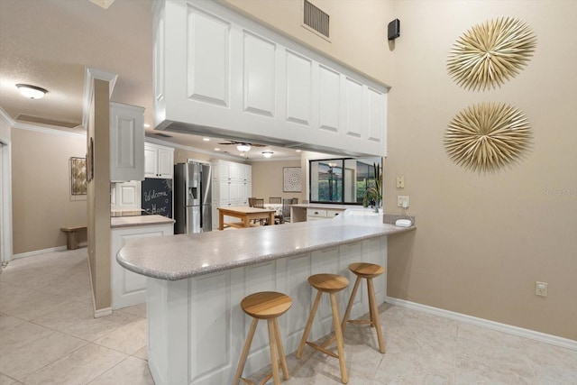 7321 Hemlock Ln, Sarasota, FL 34241 - kitchen featuring stainless steel fridge, a peninsula, ornamental molding, white cabinetry, and baseboards