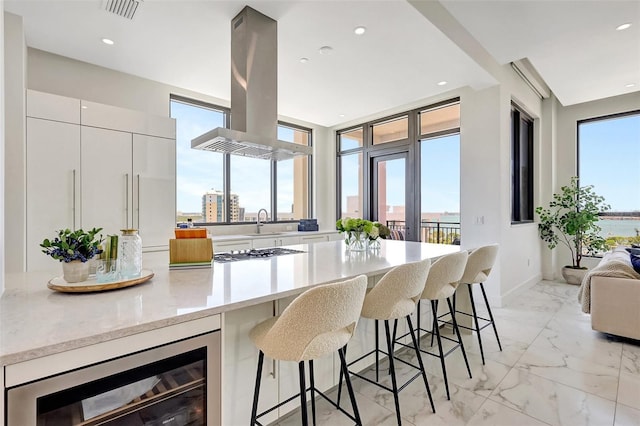 33 S Palm Ave Unit 1101, Sarasota, FL 34236 - kitchen featuring wine cooler, island range hood, white cabinetry, a breakfast bar, and recessed lighting