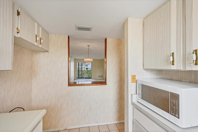 9200 Midnight Pass Rd Unit 30, Sarasota, FL 34242 - kitchen with white microwave, light countertops, a chandelier, light tile patterned floors, and baseboards