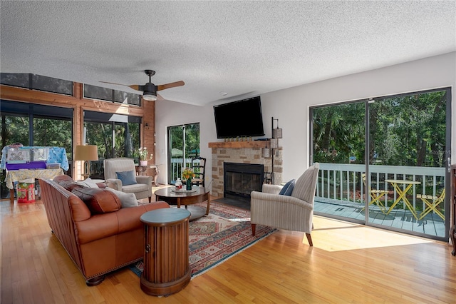 7251 Fish Farm Rd, Palmetto, FL 34221 - living area with a textured ceiling, wood finished floors, a stone fireplace, and ceiling fan