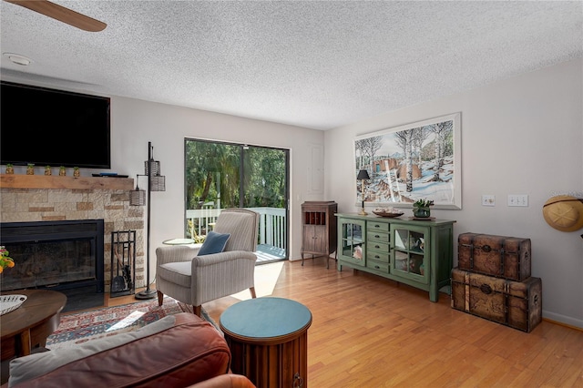 7251 Fish Farm Rd, Palmetto, FL 34221 - living room featuring wood finished floors, a textured ceiling, a stone fireplace, and a ceiling fan