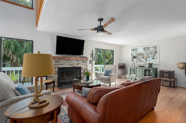 7251 Fish Farm Rd, Palmetto, FL 34221 - living room featuring a textured ceiling, a ceiling fan, a stone fireplace, and light wood-style flooring