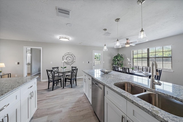 400 E Baffin Dr, Venice, FL 34293 - kitchen featuring stainless steel dishwasher, healthy amount of natural light, a textured ceiling, light wood finished floors, and white cabinetry