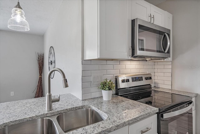 400 E Baffin Dr, Venice, FL 34293 - kitchen with stainless steel appliances, tasteful backsplash, white cabinets, light stone countertops, and decorative light fixtures