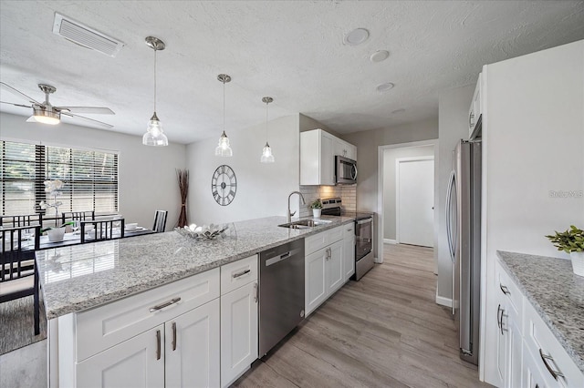 400 E Baffin Dr, Venice, FL 34293 - kitchen with stainless steel appliances, a peninsula, white cabinetry, a textured ceiling, and light wood finished floors