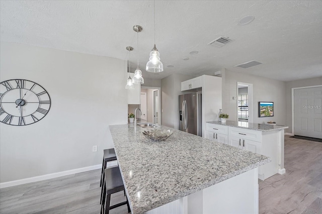 400 E Baffin Dr, Venice, FL 34293 - kitchen with stainless steel refrigerator with ice dispenser, a peninsula, light wood-style flooring, white cabinets, and a kitchen breakfast bar