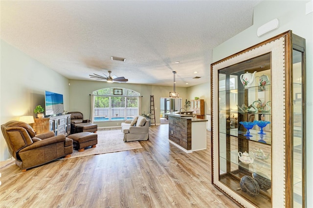 11254 82nd St E, Parrish, FL 34219 - living area with light wood-type flooring, a textured ceiling, and a ceiling fan