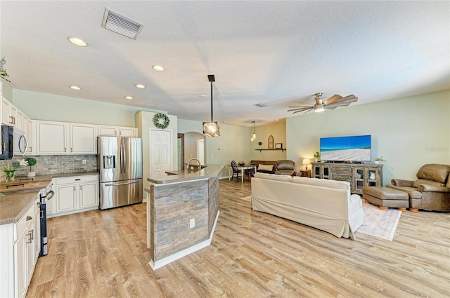 11254 82nd St E, Parrish, FL 34219 - kitchen with appliances with stainless steel finishes, open floor plan, light wood-type flooring, white cabinets, and a textured ceiling